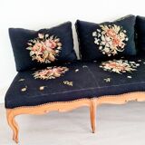 Old bench upholstered in black canvas flowers