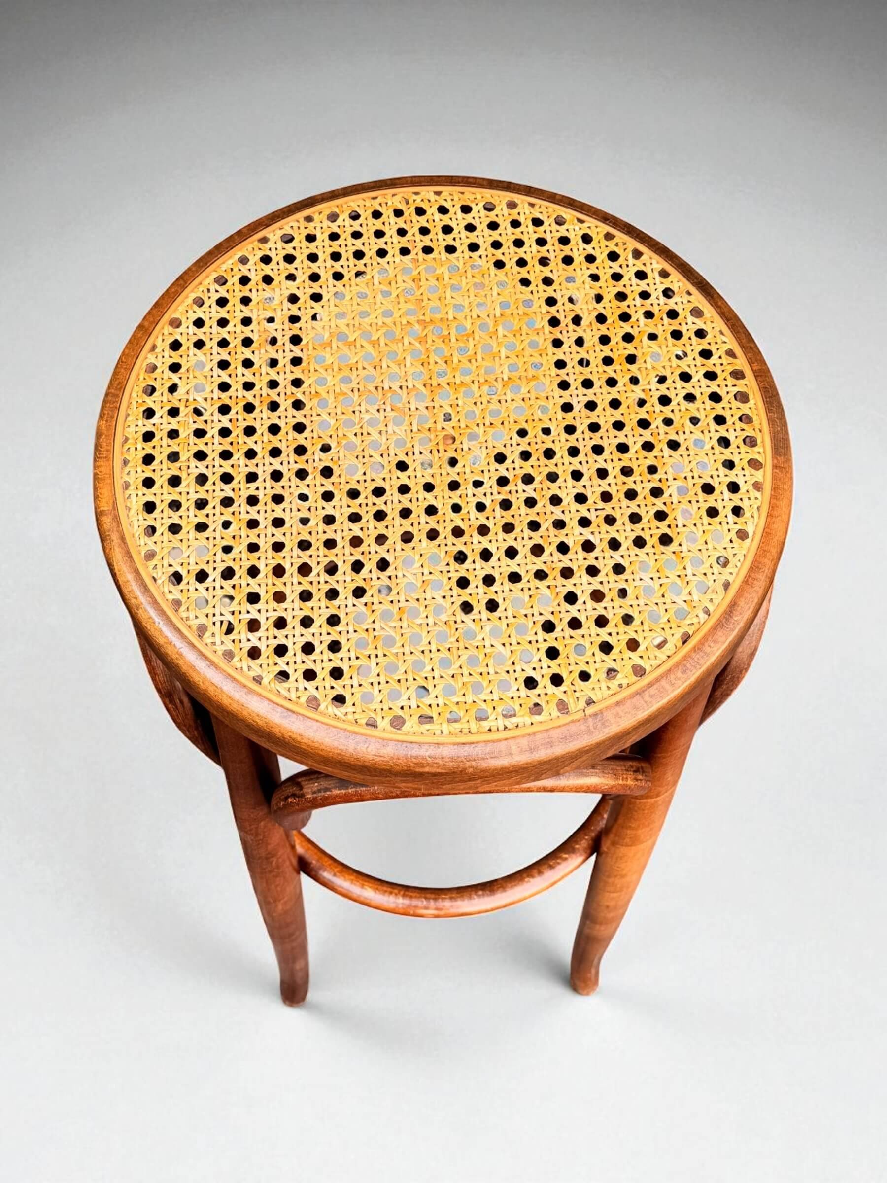 Old high stool in curved wood with caned seat