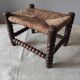 Antique wooden turned spool footrest with straw.