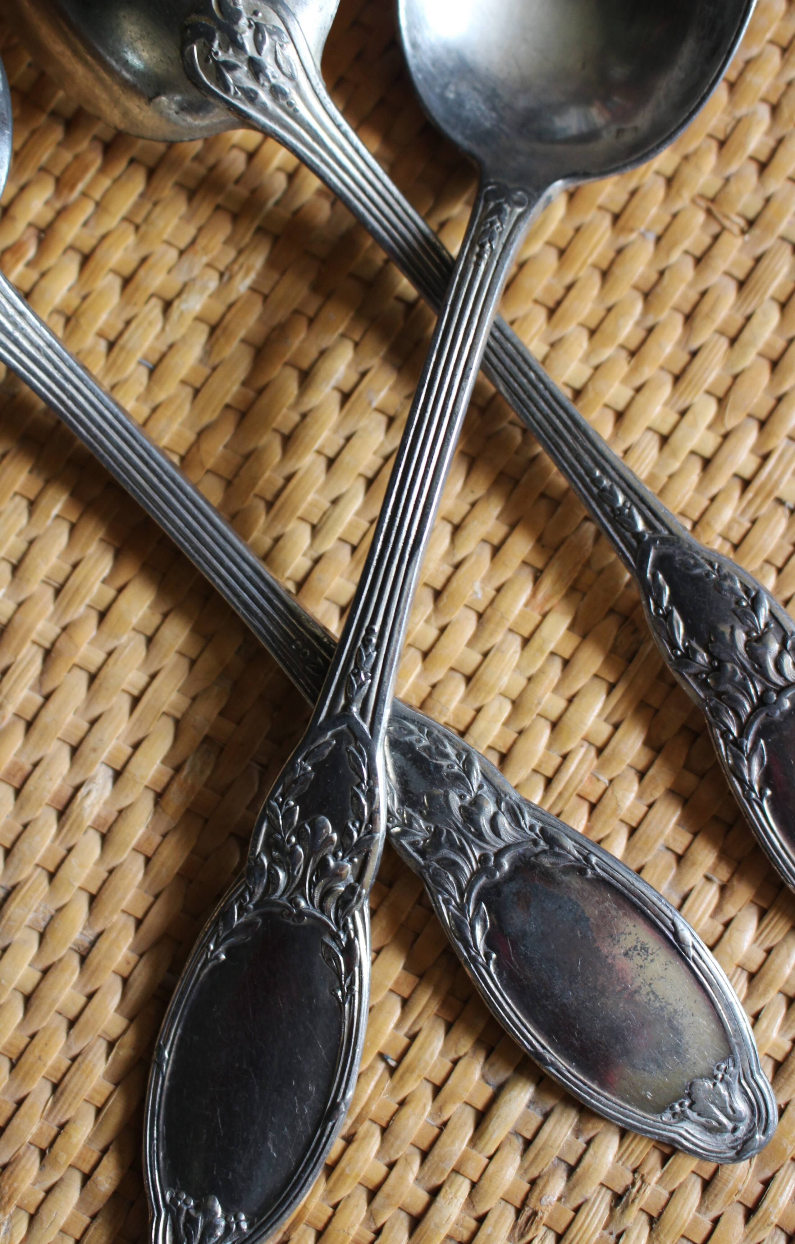 A set of 6 silver-plated metal soup spoons with foliage design.