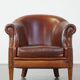 Un fauteuil club robuste mais confortable en cuir de mouton et fini avec des clous décoratifs