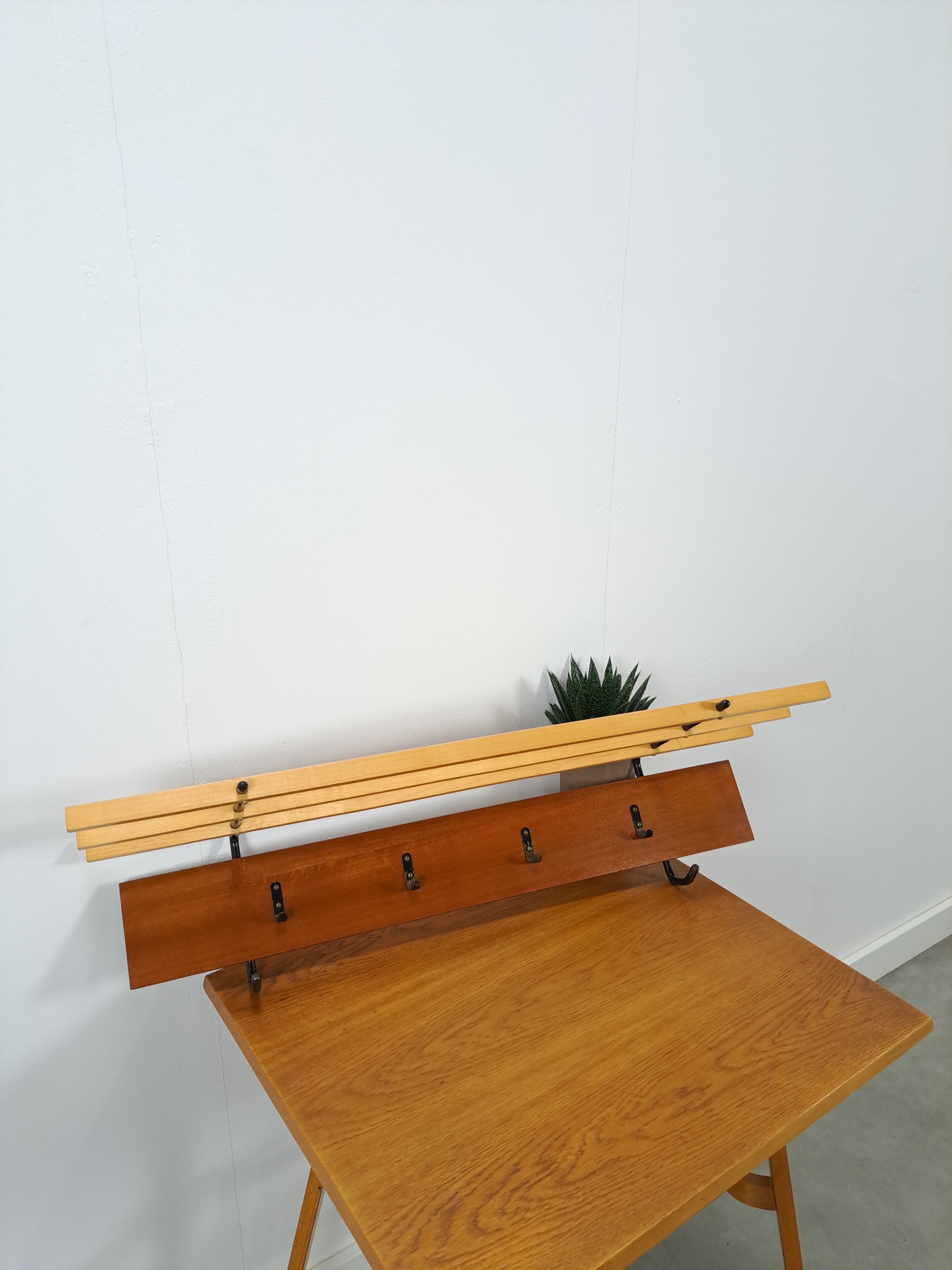 Vintage wall coat rack with black hooks and light wood