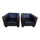 2 club armchairs with a chocolate faux leather seat and backrest and wooden legs.
