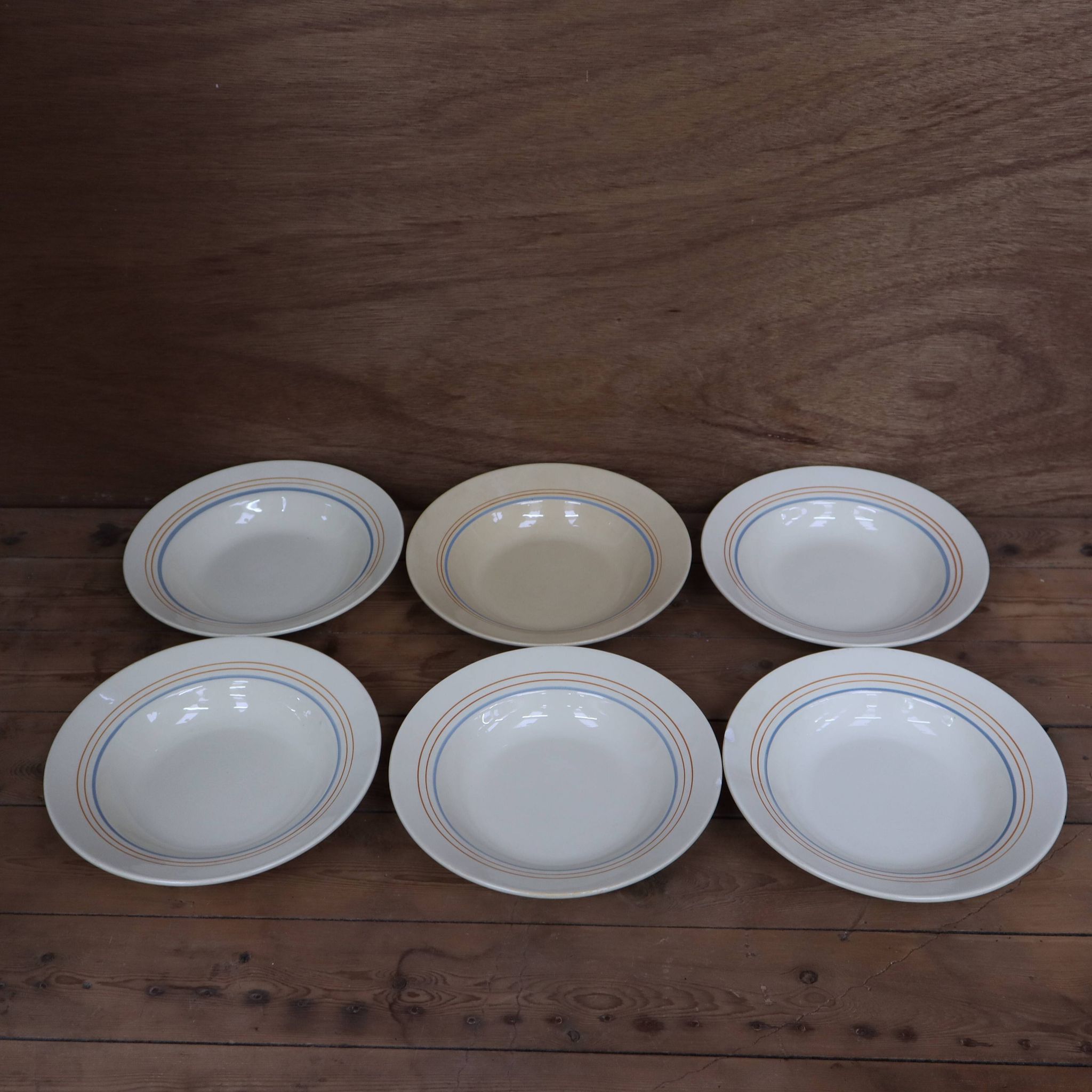 6 old cream-coloured deep plates with blue/orange trim.