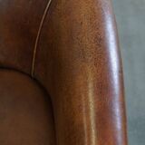 Subtle, neat sheepskin leather club armchair with a fixed seat cushion in a deep, dark cognac color
