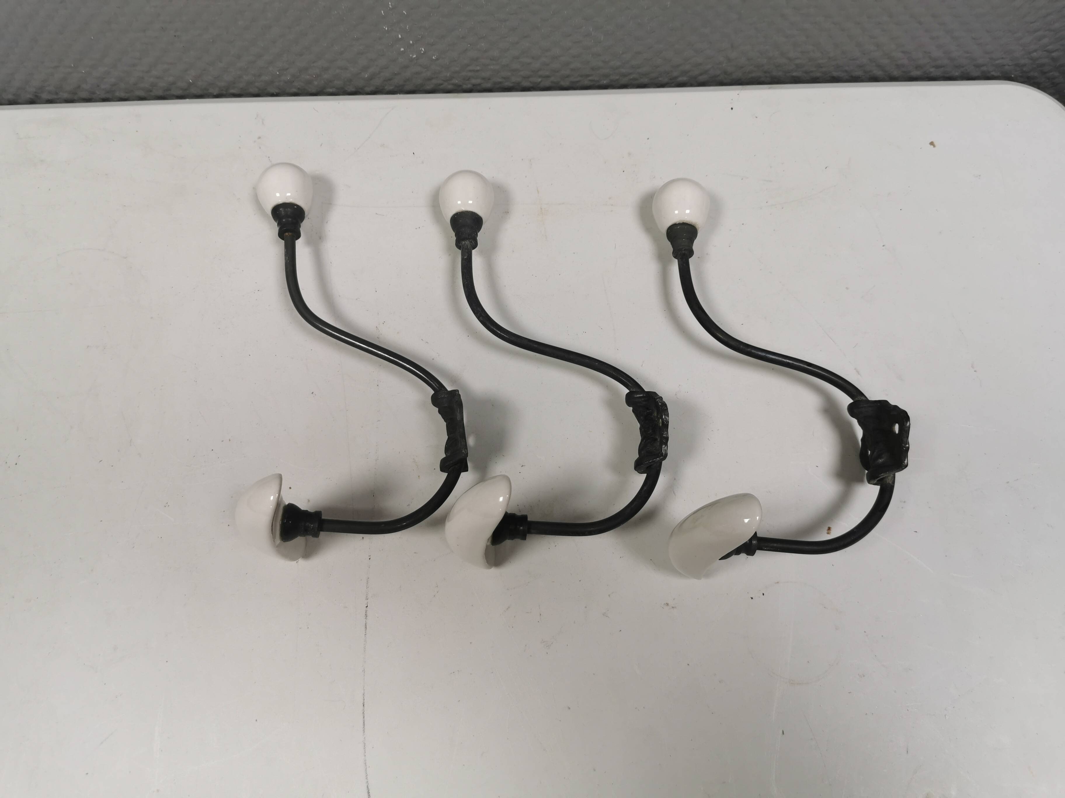 Coat hooks made of galvanized brass and raw white porcelain
