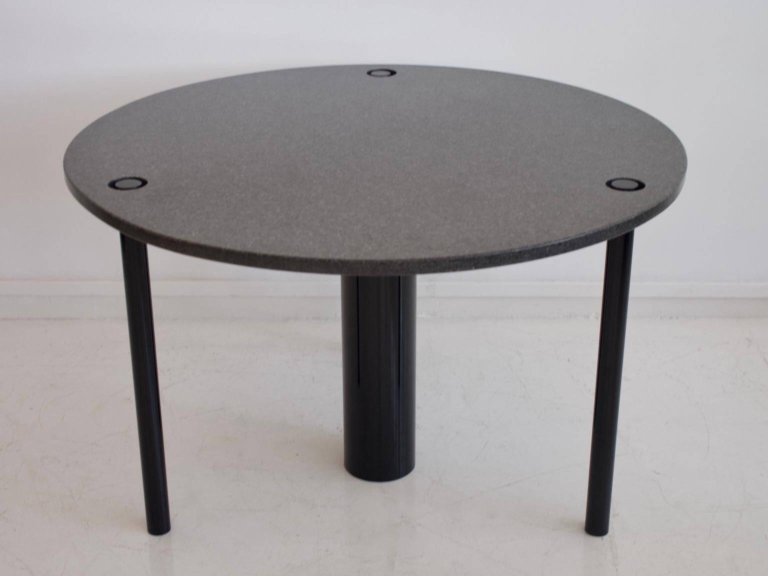 Round dining table in black lacquered metal with a granite top.