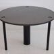Round dining table in black lacquered metal with a granite top.