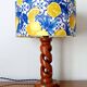 Turned wooden lamp with a lampshade featuring lemon tiles.