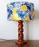 Turned wooden lamp with a lampshade featuring lemon tiles.