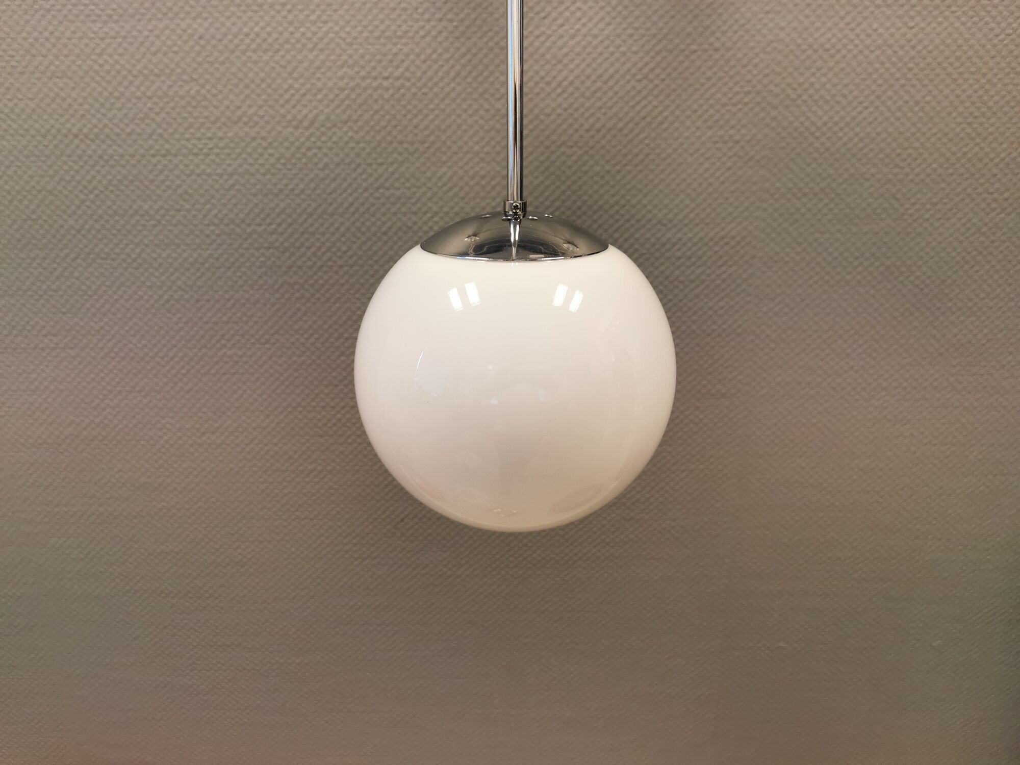 White hanging lamp with metal suspension, made with ball round opal glass shade.