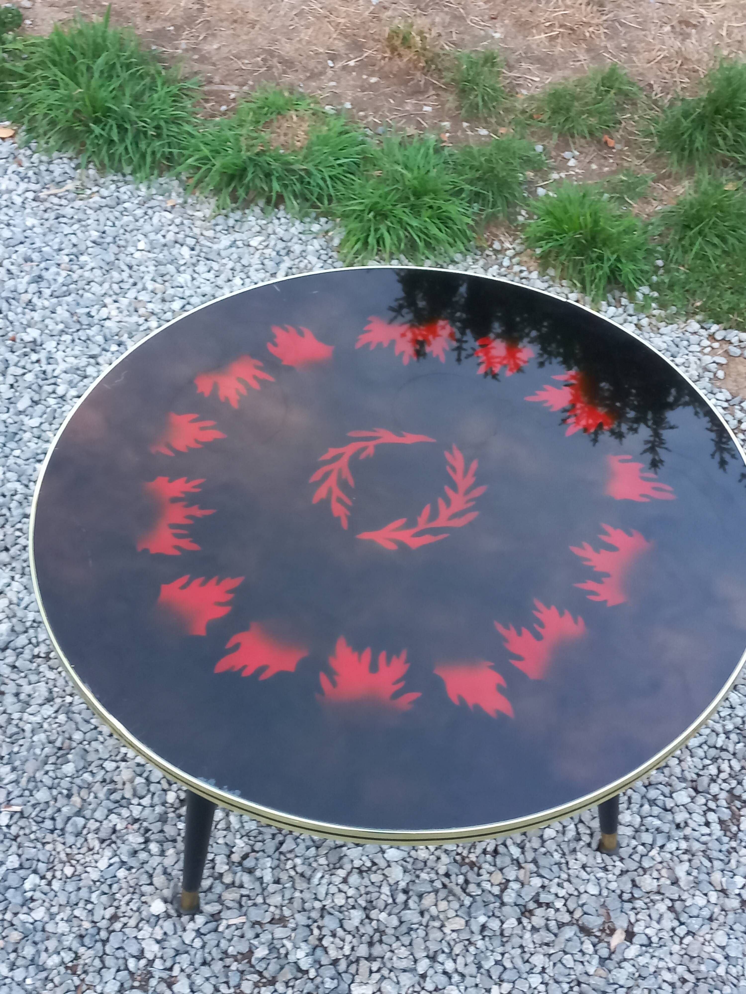 Vintage coffee table with glass top and tripod legs in blackened wood from the 1960s.