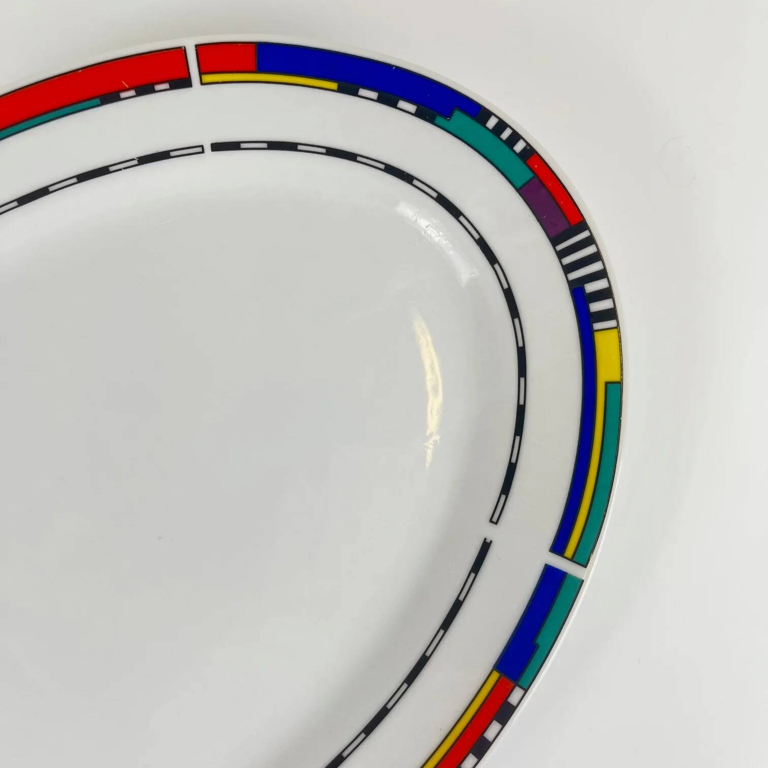 Oval porcelain plate by Van Well, multicoloured geometric border, 1980.