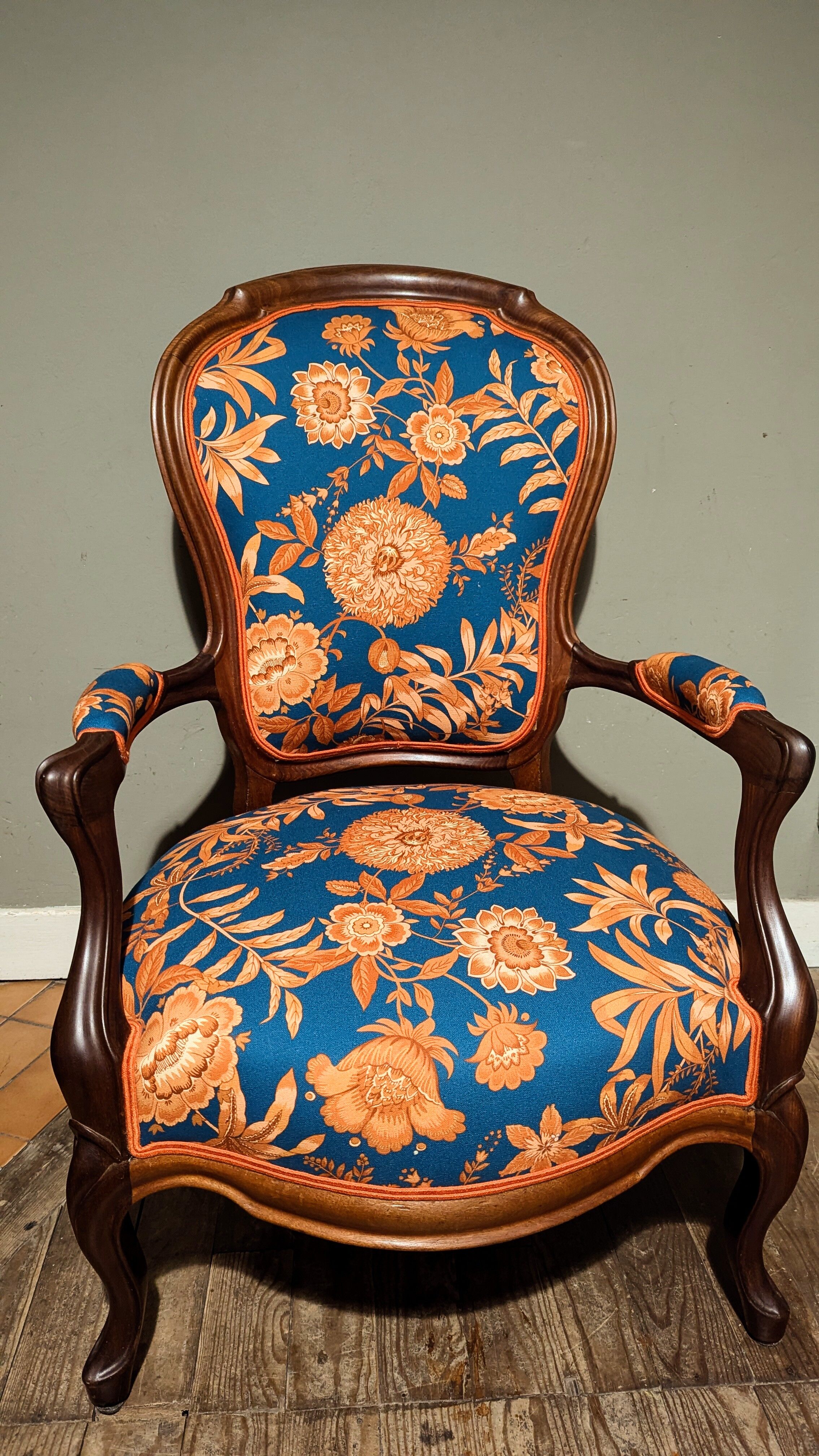 Restored Louis-Philippe cabriolet armchair, blue and orange floral fabric.
