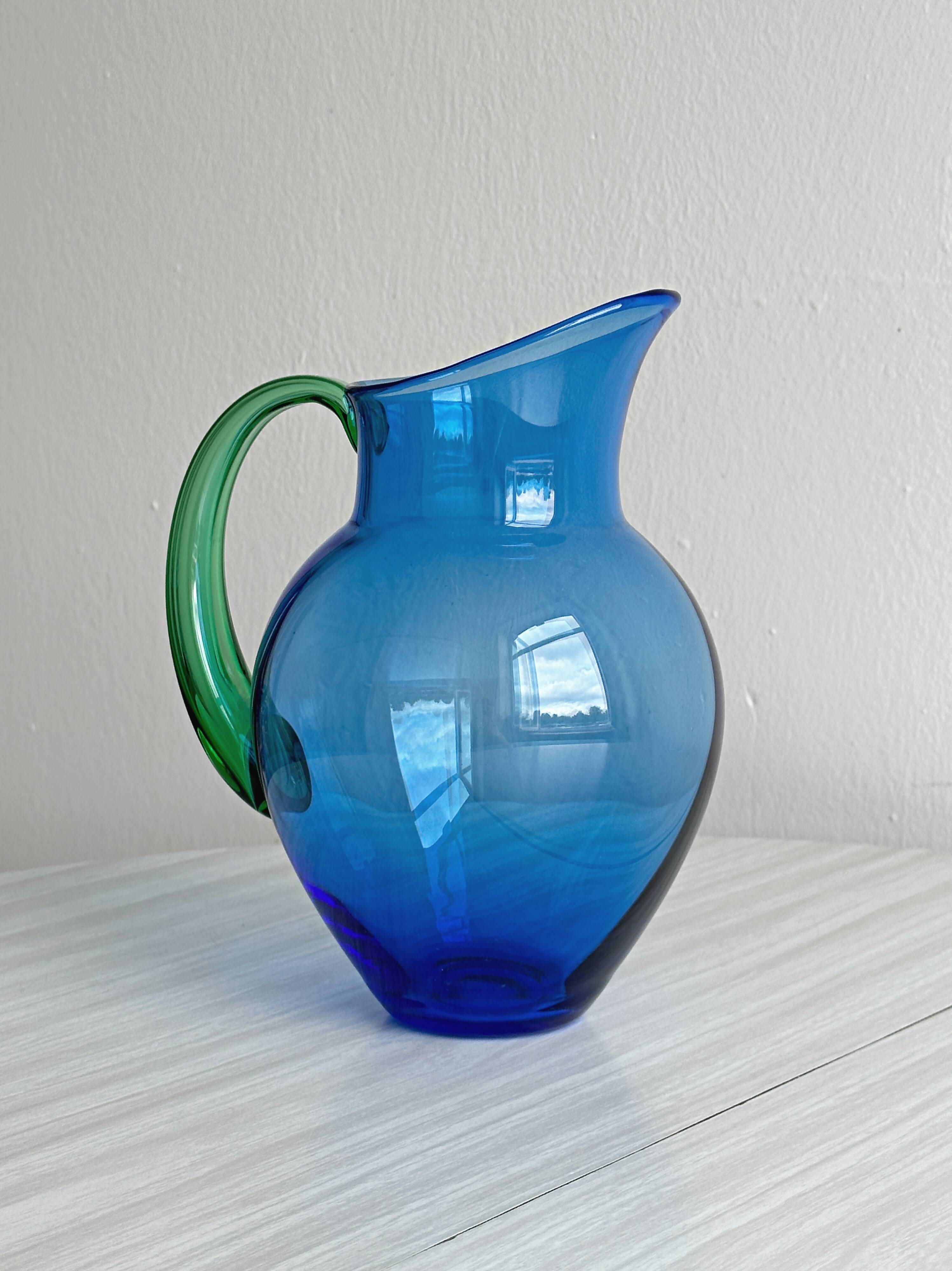 Translucent blue glass jug with a green handle.
