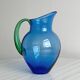 Translucent blue glass jug with a green handle.