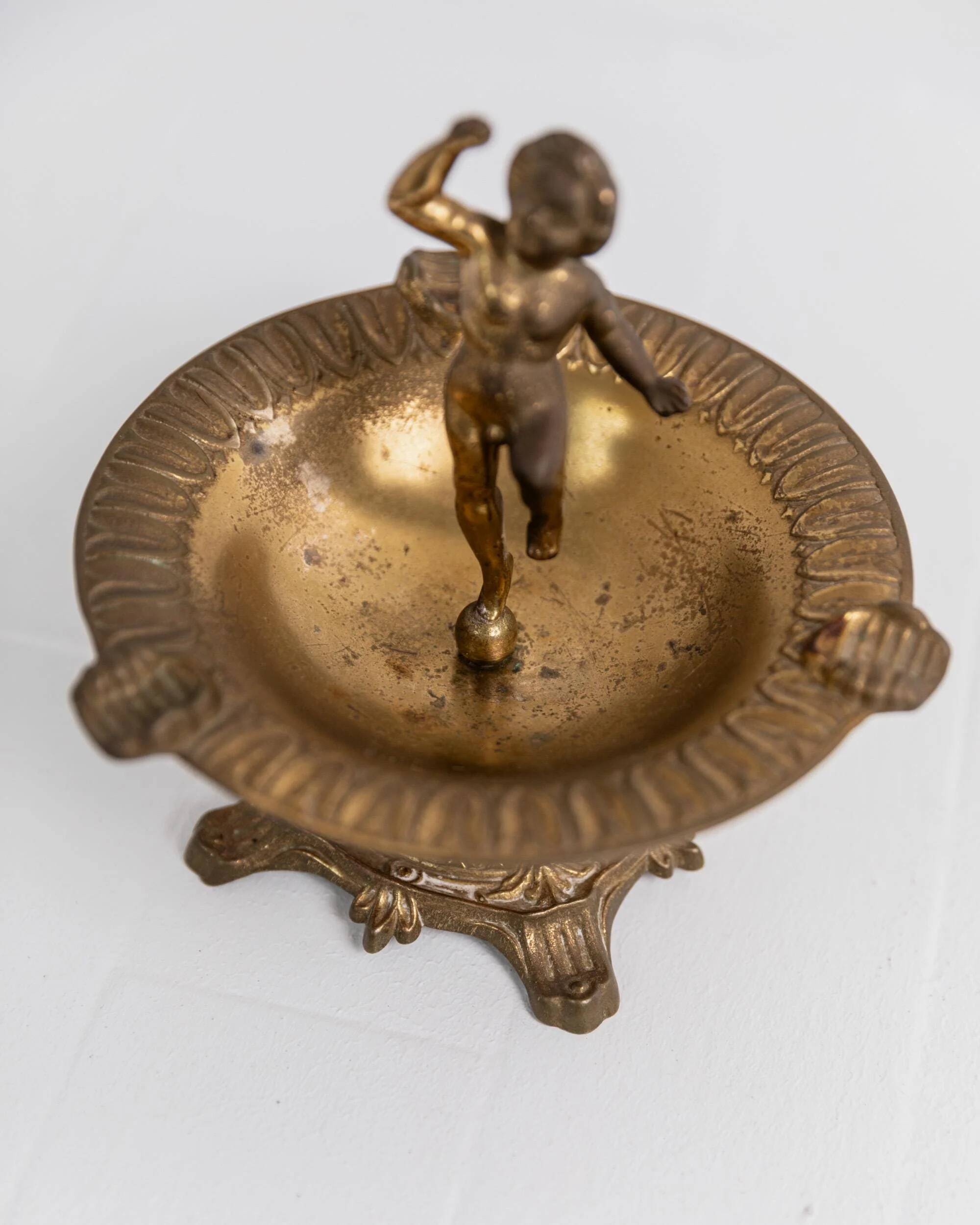 Vintage brass ashtray from the 1940s with a nude boy figurine on a footed base.