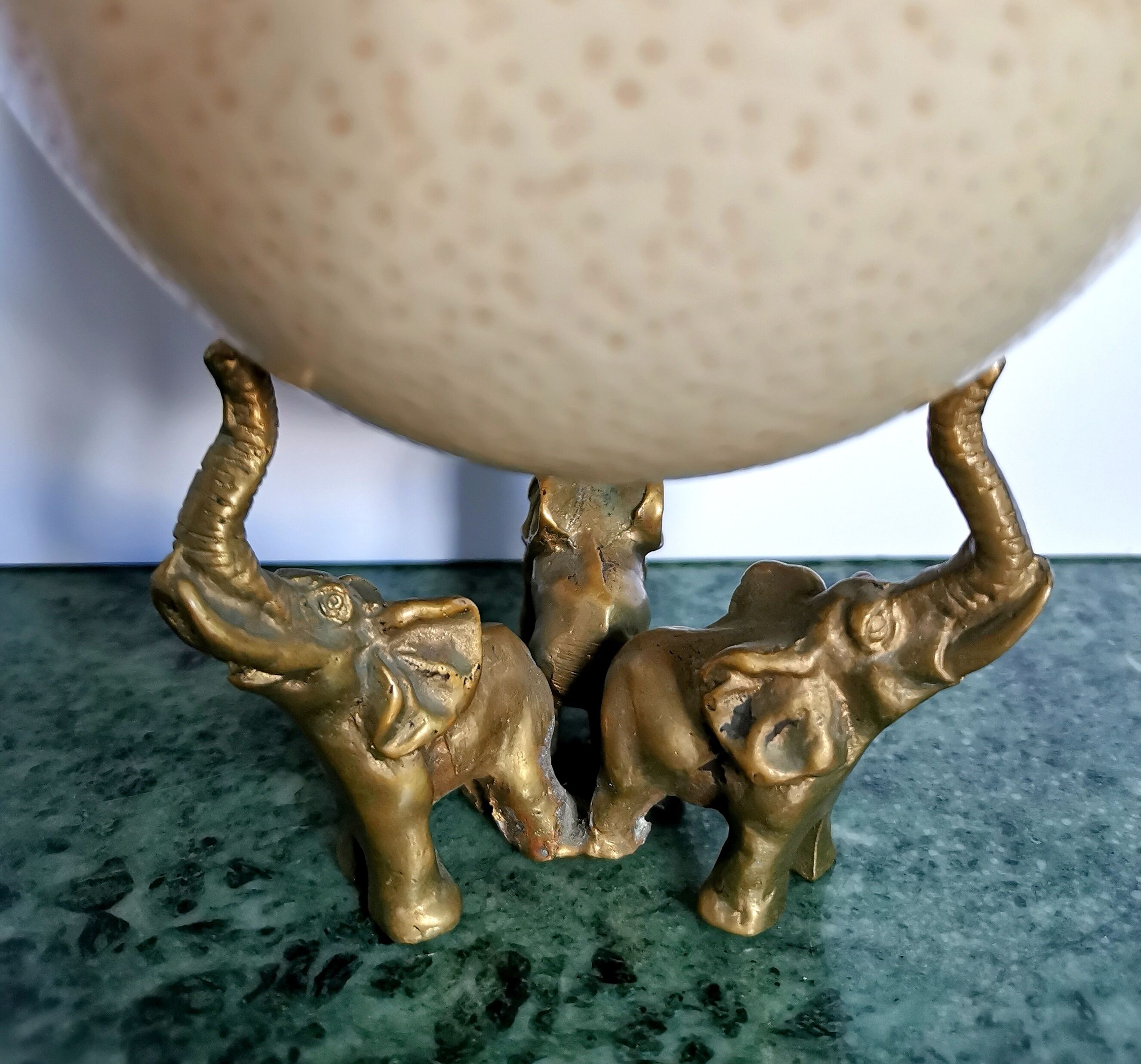 Ancient ostrich egg naturalized on bronze base representing 3 elephants