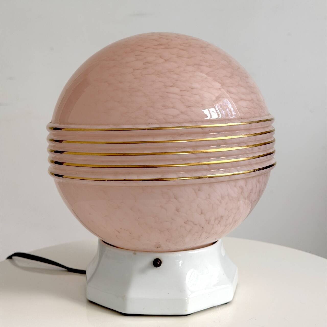 Art Deco lamp with a speckled pink glass globe and a white ceramic base.