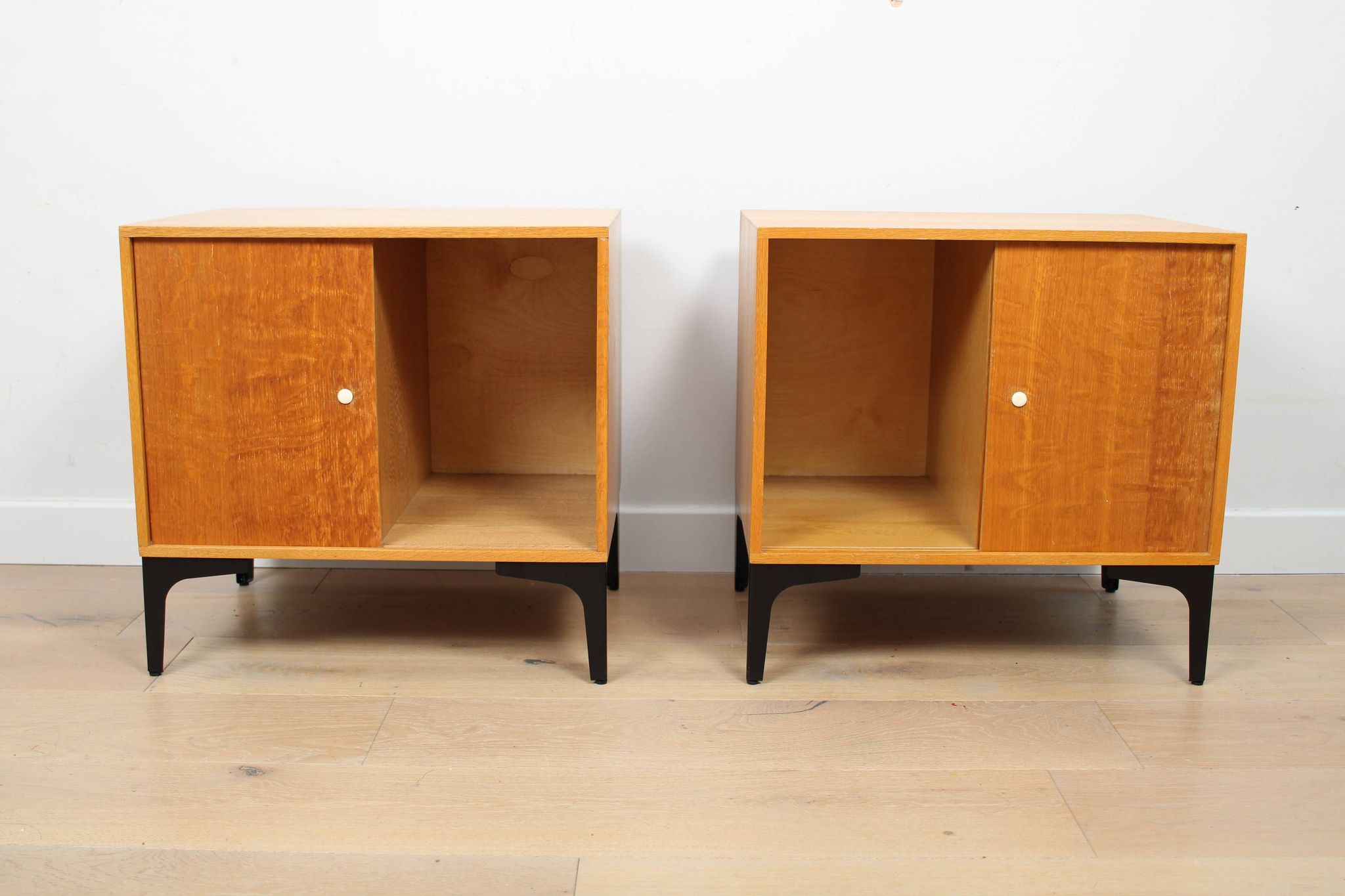A pair of vintage mid-century bedside tables with oak sliding doors
