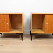 A pair of vintage mid-century bedside tables with oak sliding doors