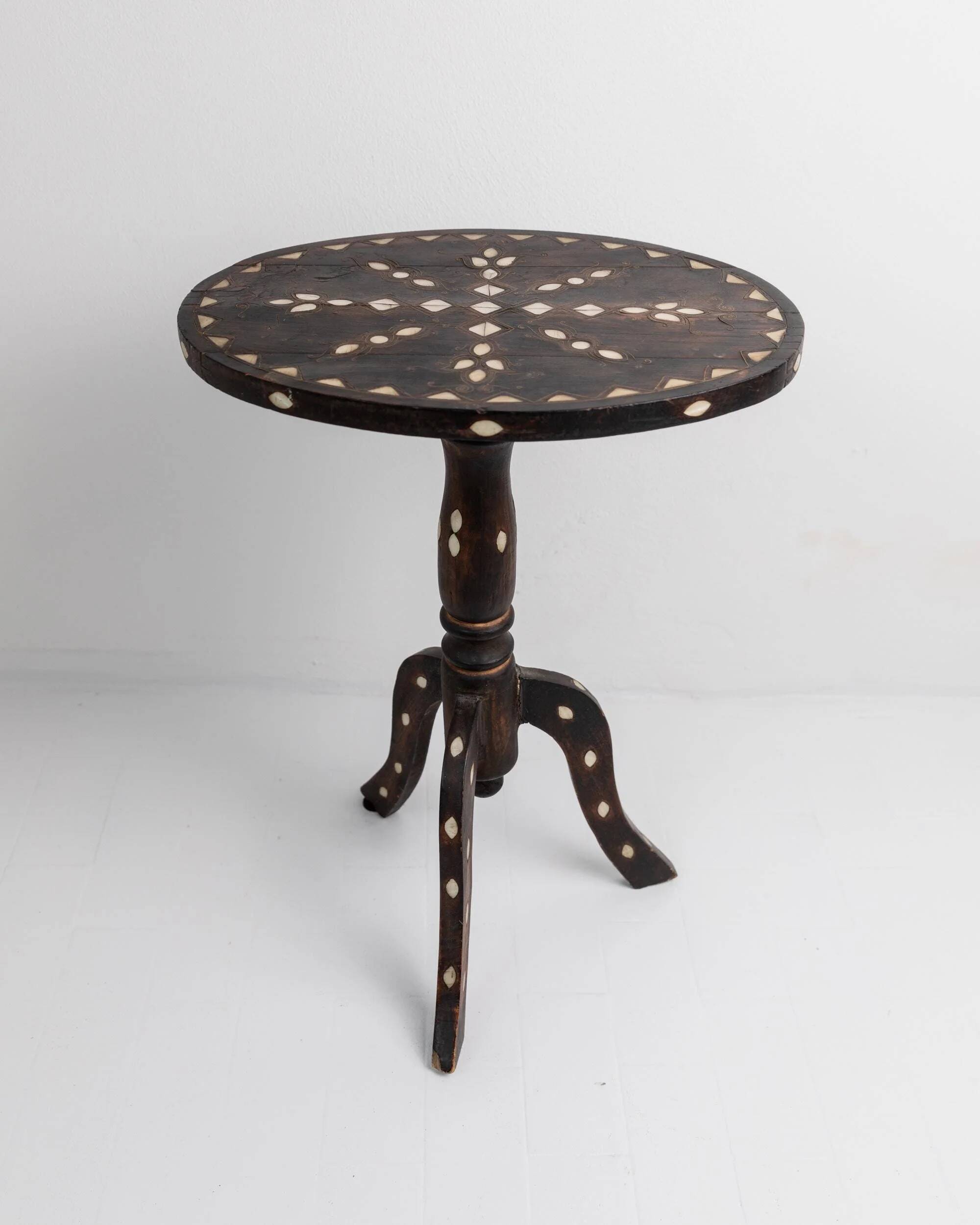 Vintage side table from the early 19th century, dark wood with mother-of-pearl inlays, oval shape with three legs, ethnic style.