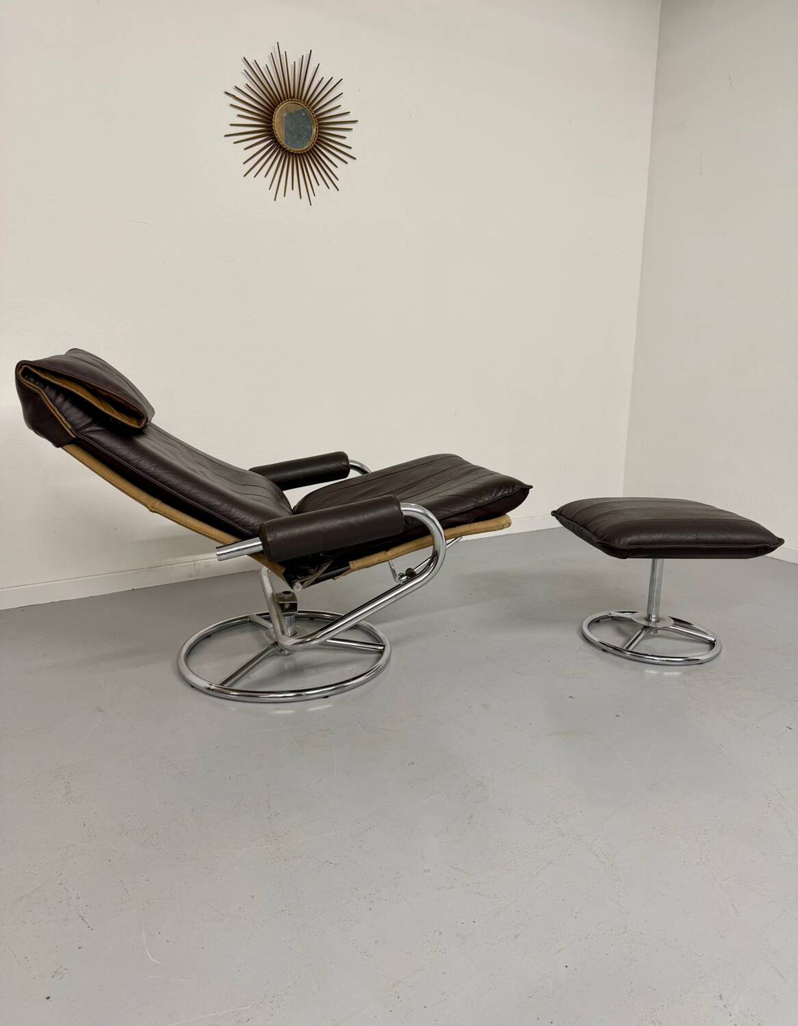 Vintage leather reclining armchair and its 1970s designer ottoman.