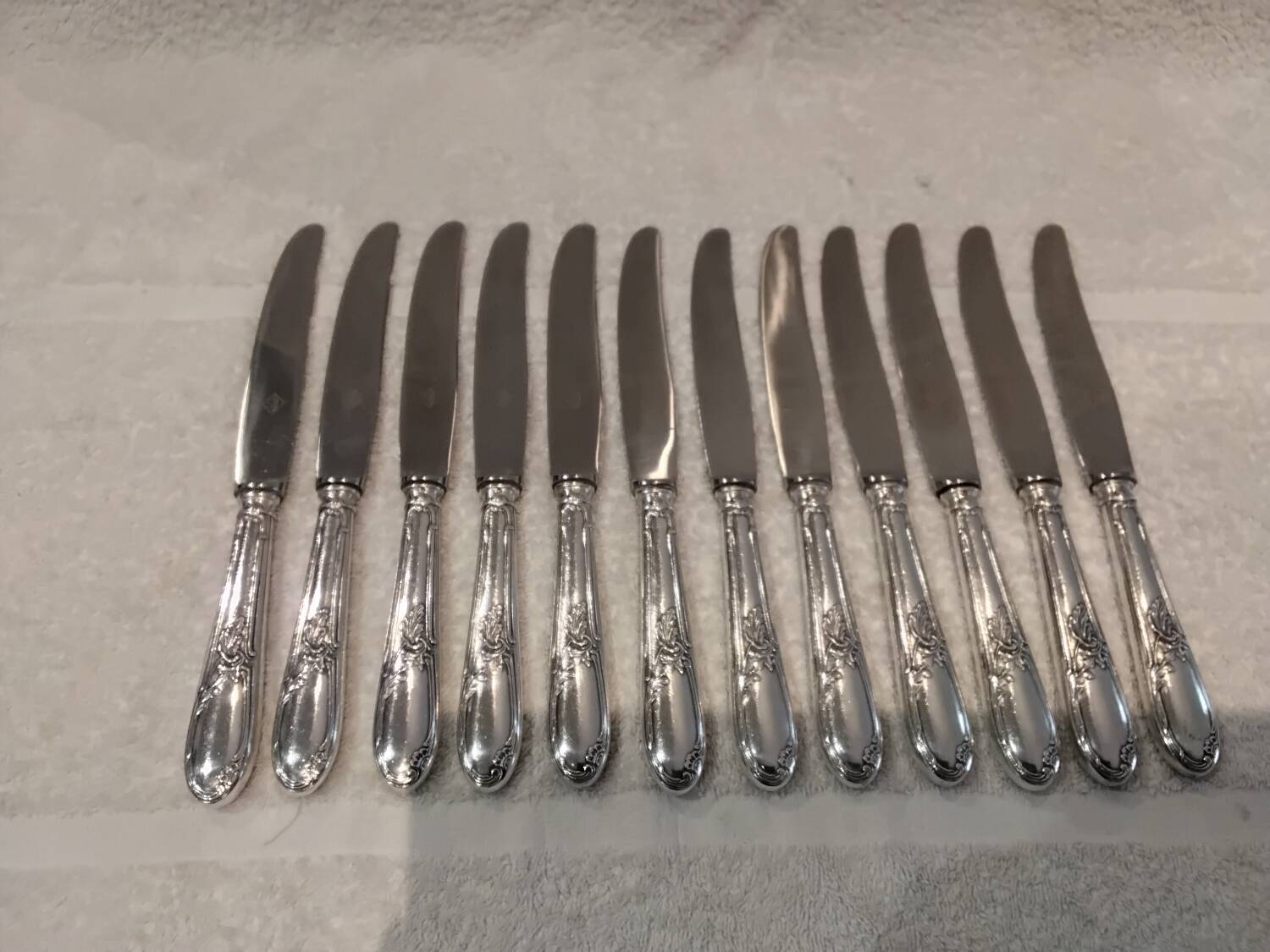 12 silver-plated metal table knives with rocaille ribbon decoration, 25.1 cm