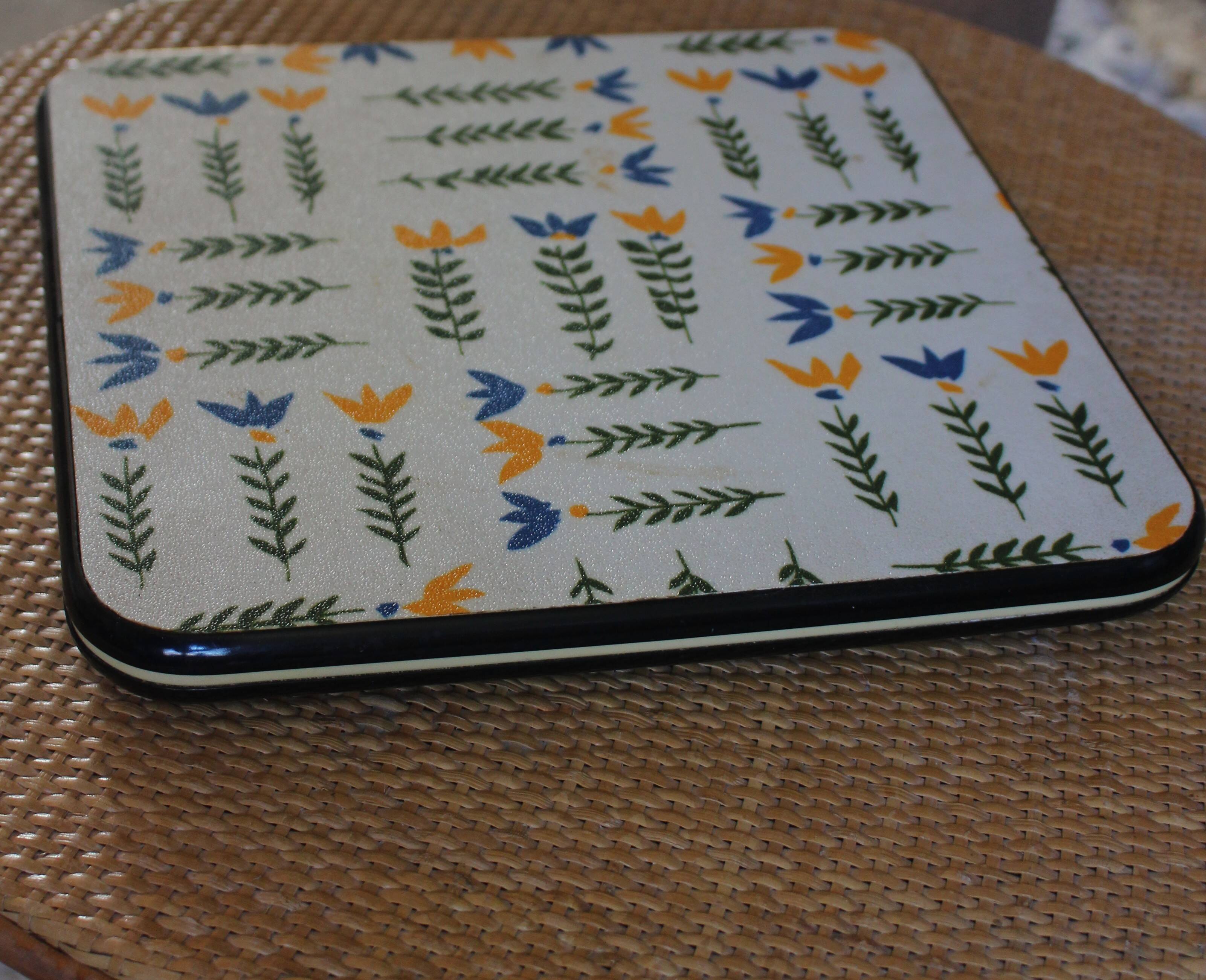 Vintage laminated wooden trivet with yellow, green, and blue flowers