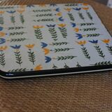 Vintage laminated wooden trivet with yellow, green, and blue flowers