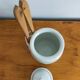 Vintage porcelain pickle pot with wooden pliers.