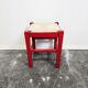 Tabouret en bois rouge avec assise en paille tressée.
