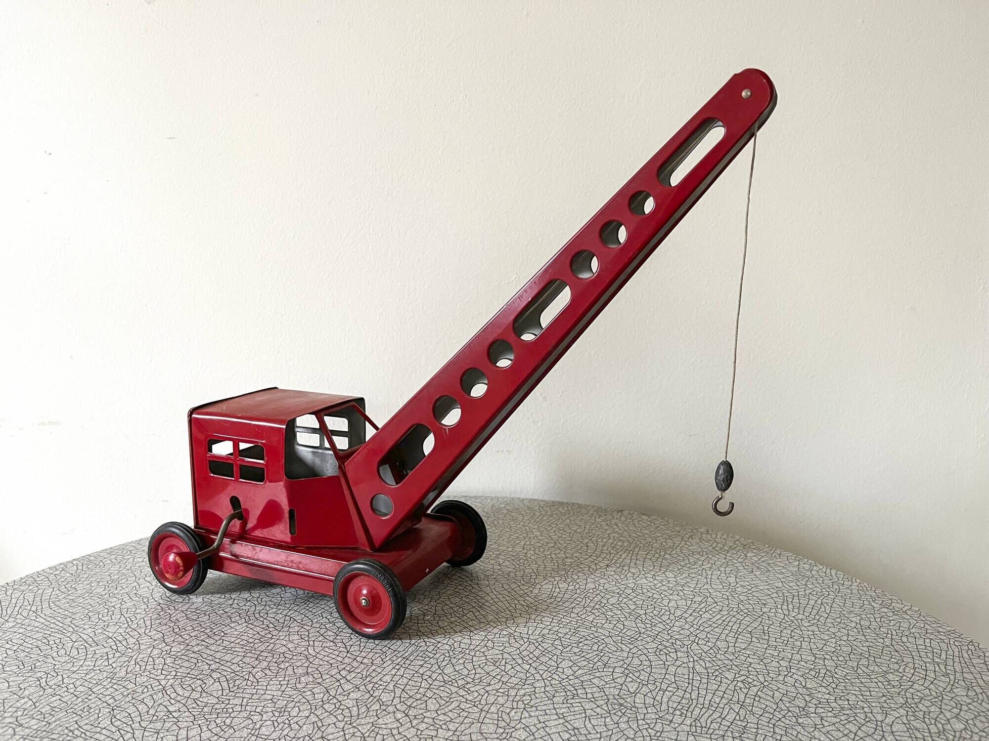Grue de chantier rouge en tôle datant des années 60 avec mécanisme manuel