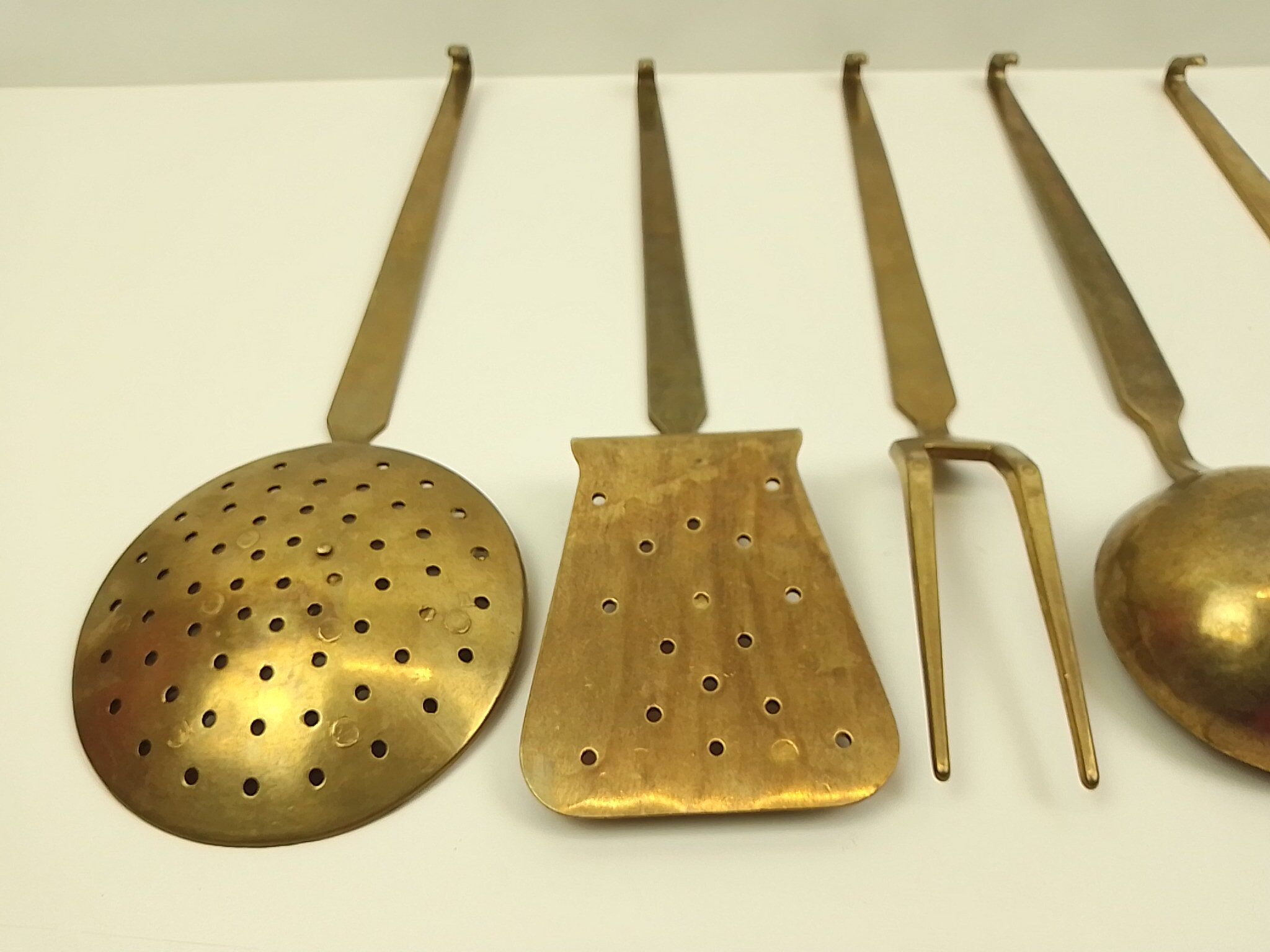 5 kitchen utensils and a brass wall mount