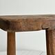 Antique three-legged stool made of raw solid wood.