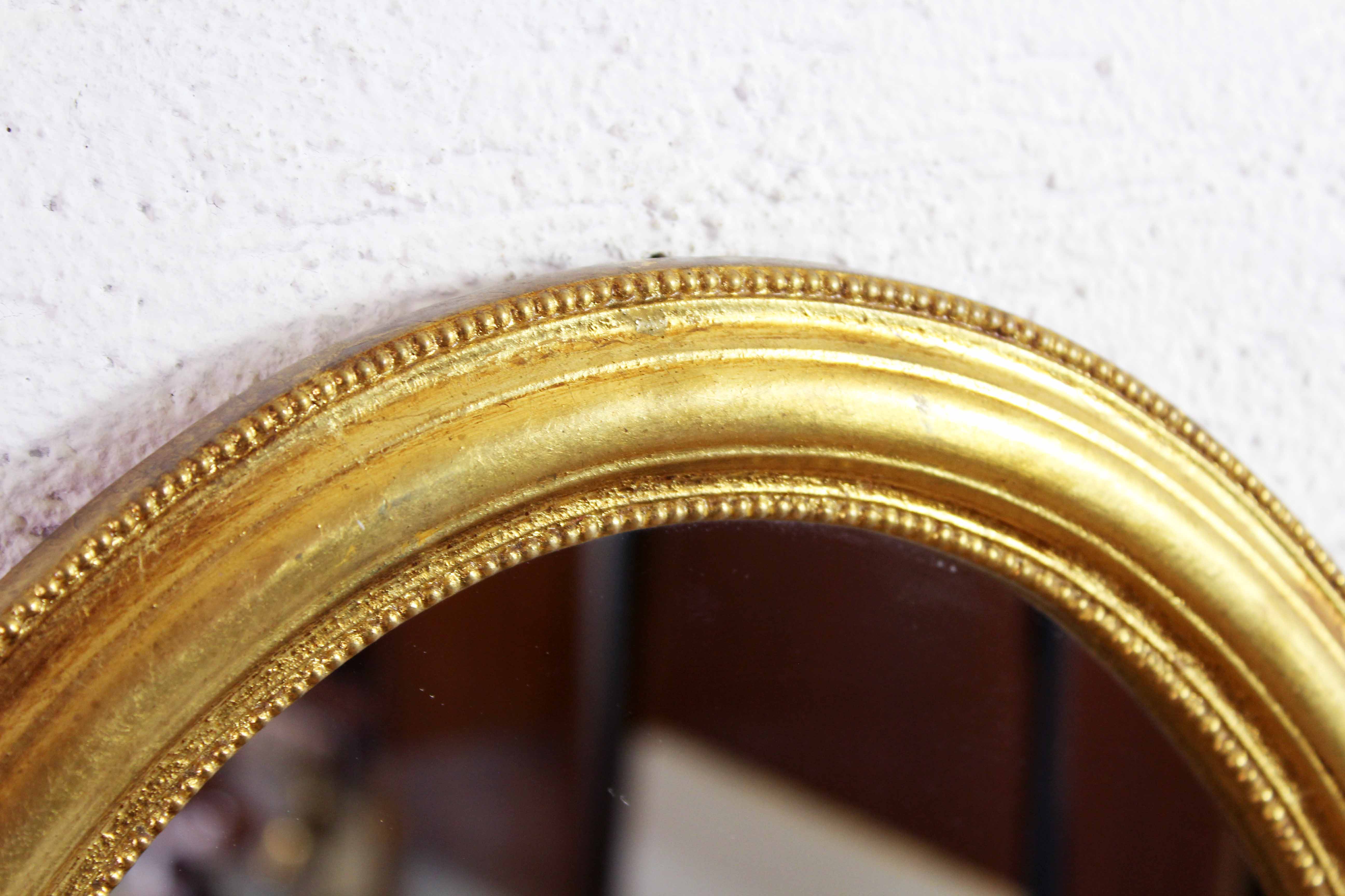Golden oval mirror with leaf