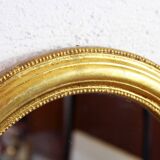 Golden oval mirror with leaf