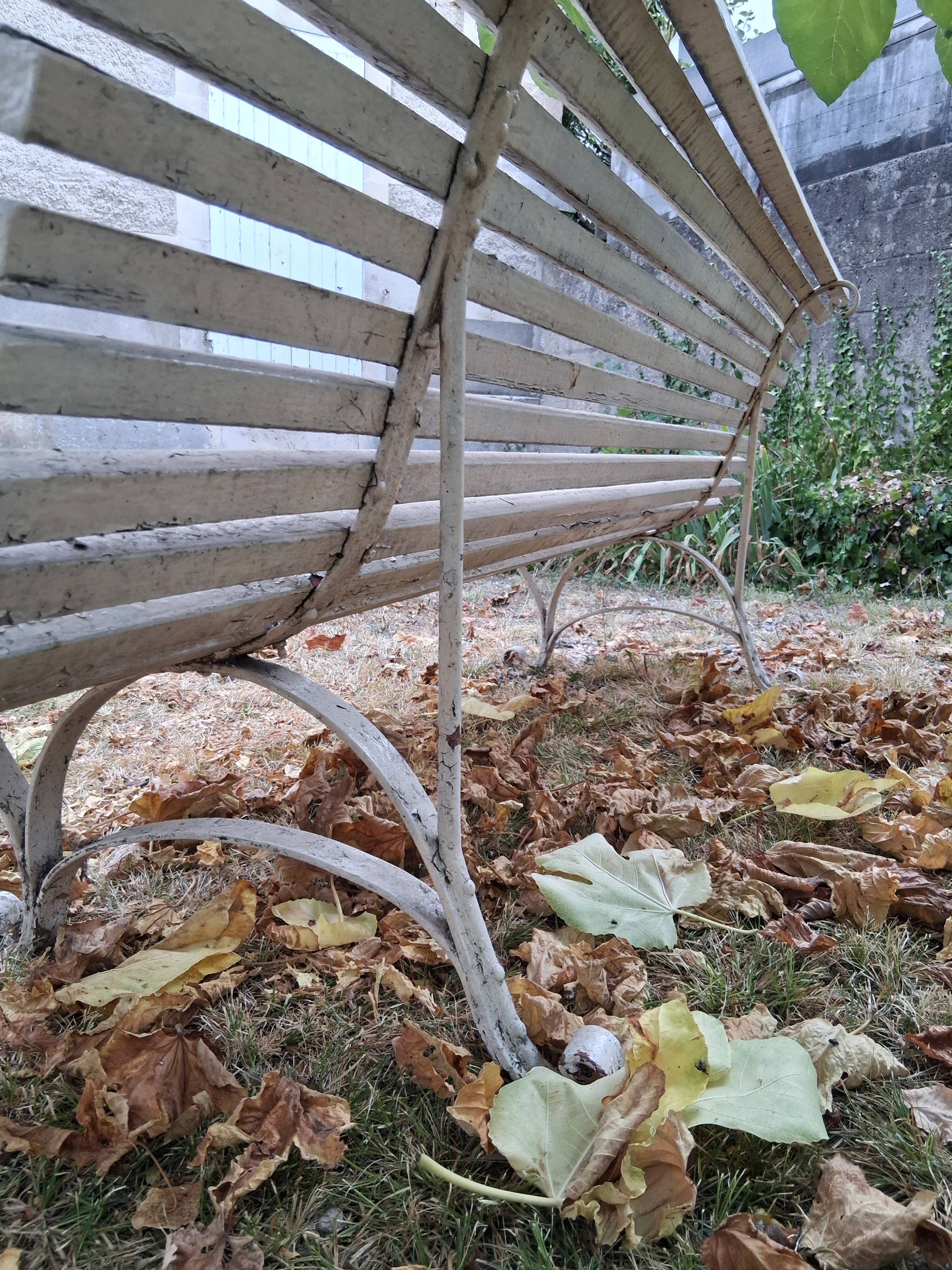 Pair of antique wooden slatted benches with wrought iron legs.