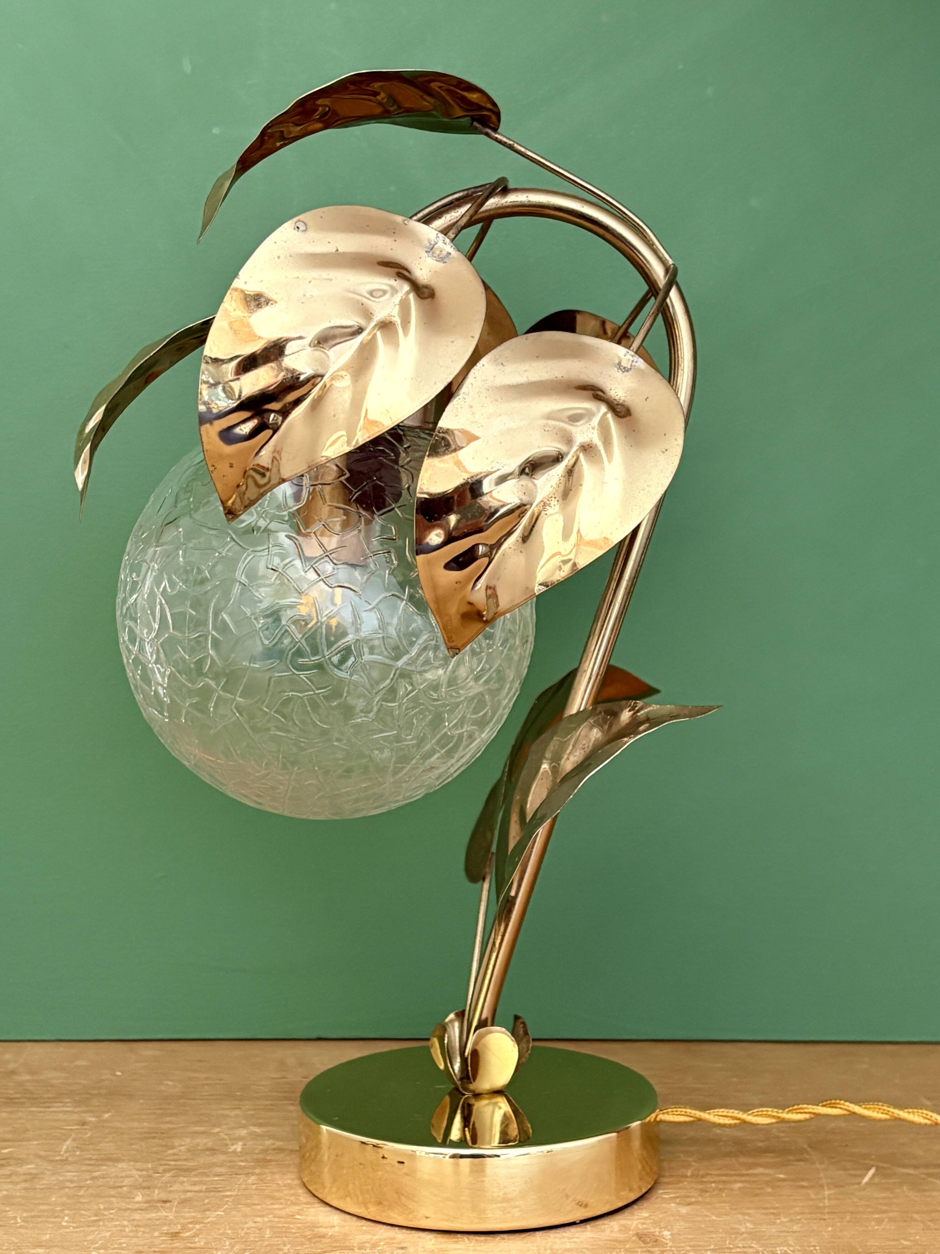 Vintage lamp with brass leaf design and transparent glass globe.