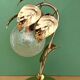 Vintage lamp with brass leaf design and transparent glass globe.