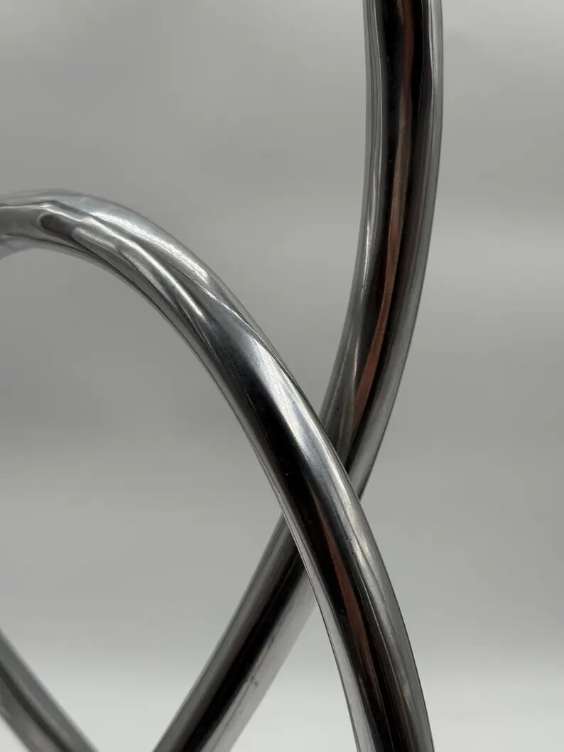 Chromed sculptural art object, abstract modernist shape in metal, contemporary design accent, brutalist interior decoration.
