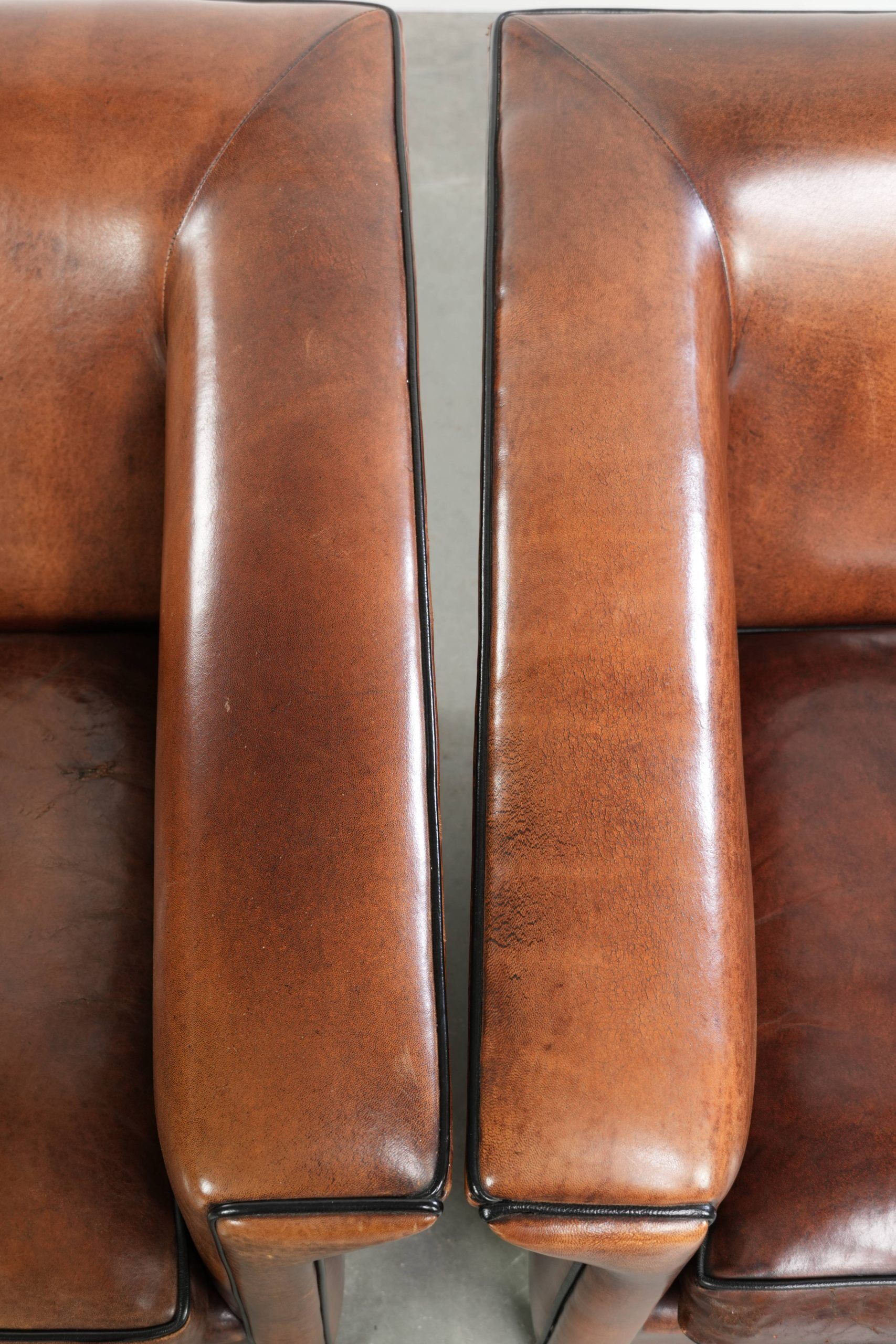 Ensemble de deux fauteuils en peau de mouton au design Art Déco avec passepoil noir.