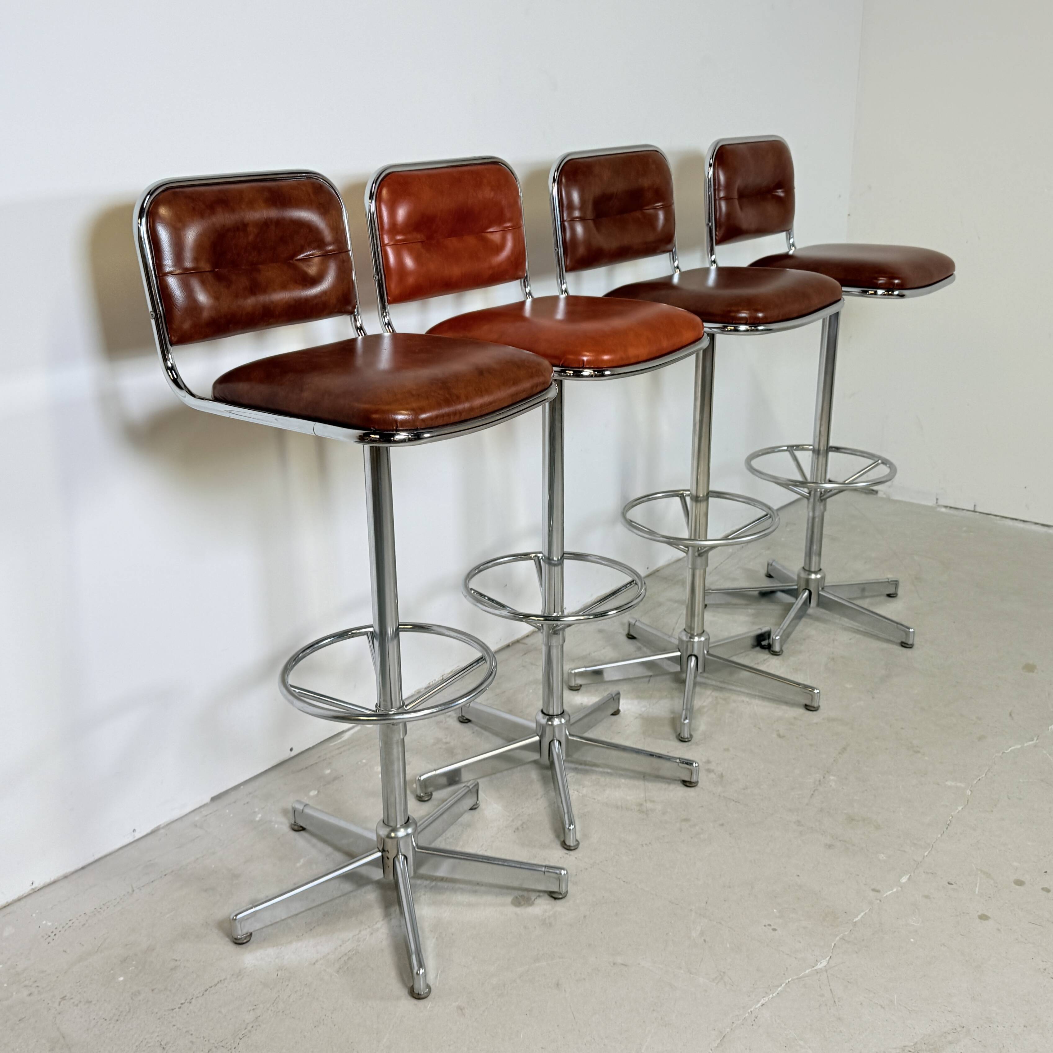 1970s chrome bar stools with cognac-colored faux leather upholstery