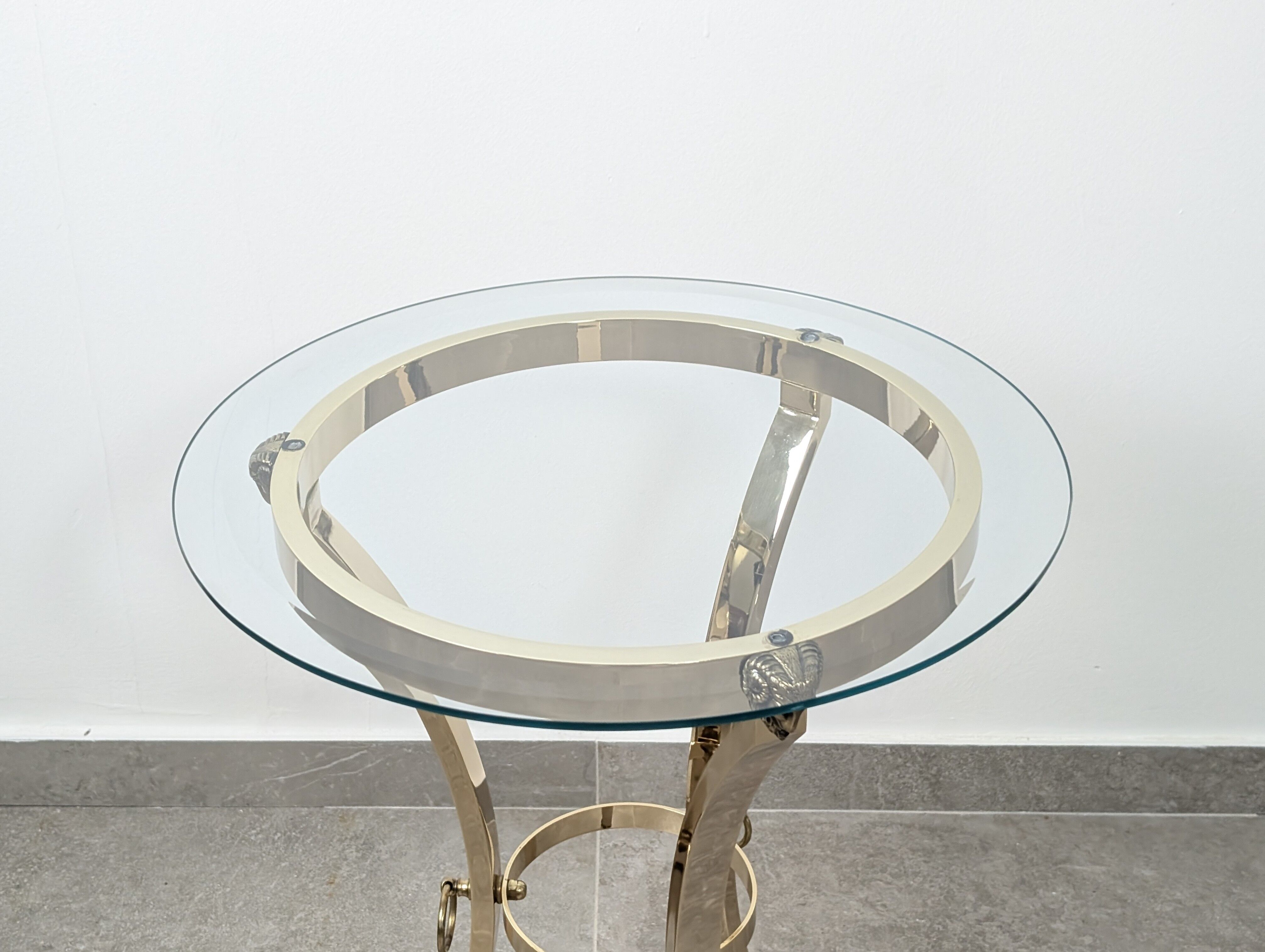 Neoclassical side table in brass and bevelled glass with ram's heads, 1970s.