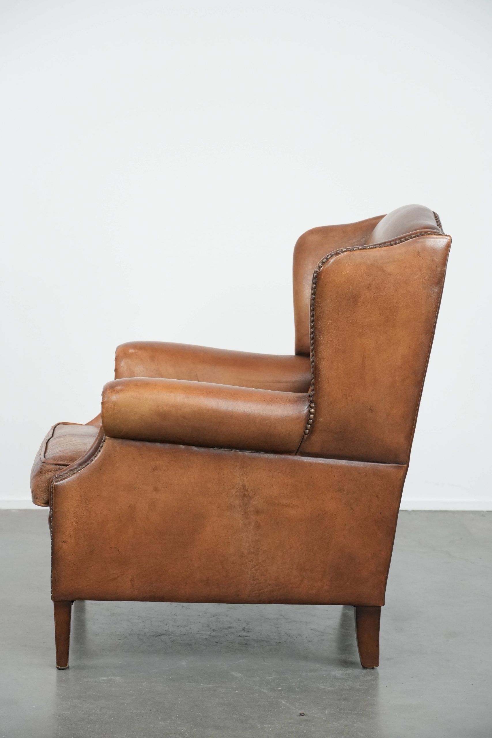 Fauteuil à oreilles en cuir de mouton charmant avec des couleurs chaudes.