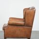 Fauteuil à oreilles en cuir de mouton charmant avec des couleurs chaudes.