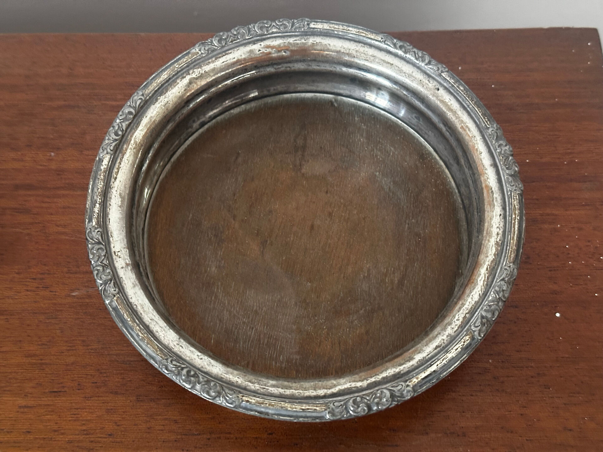 Antique silver-plated bottle coaster with floral decoration.