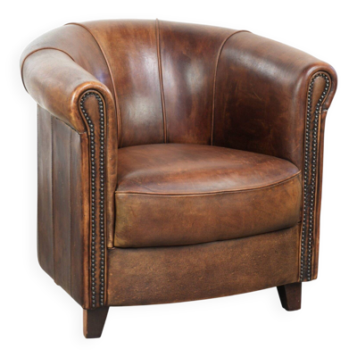 Fauteuil club en peau de mouton avec une belle patine, fini avec des clous décoratifs.