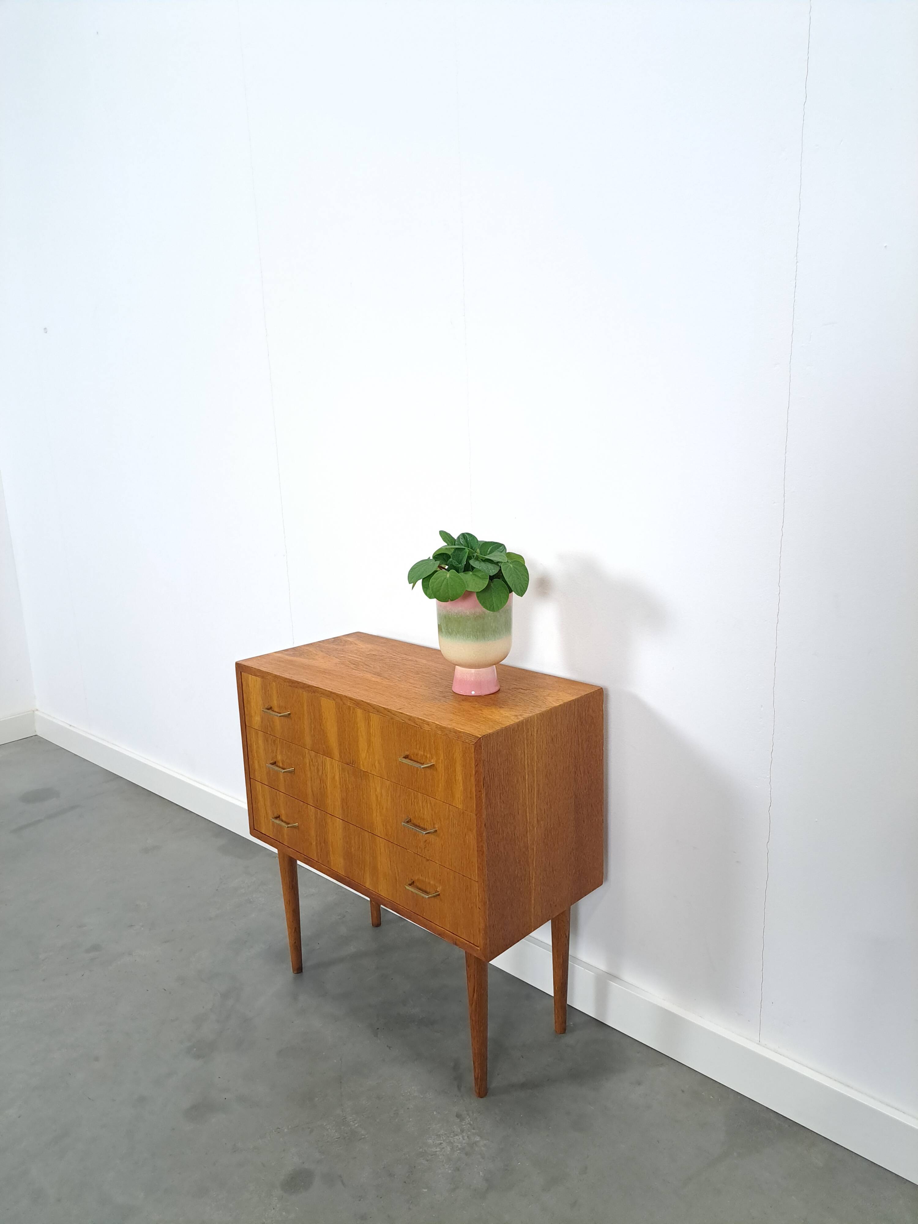 Commode danoise avec de hauts pieds et des poignées dorées.