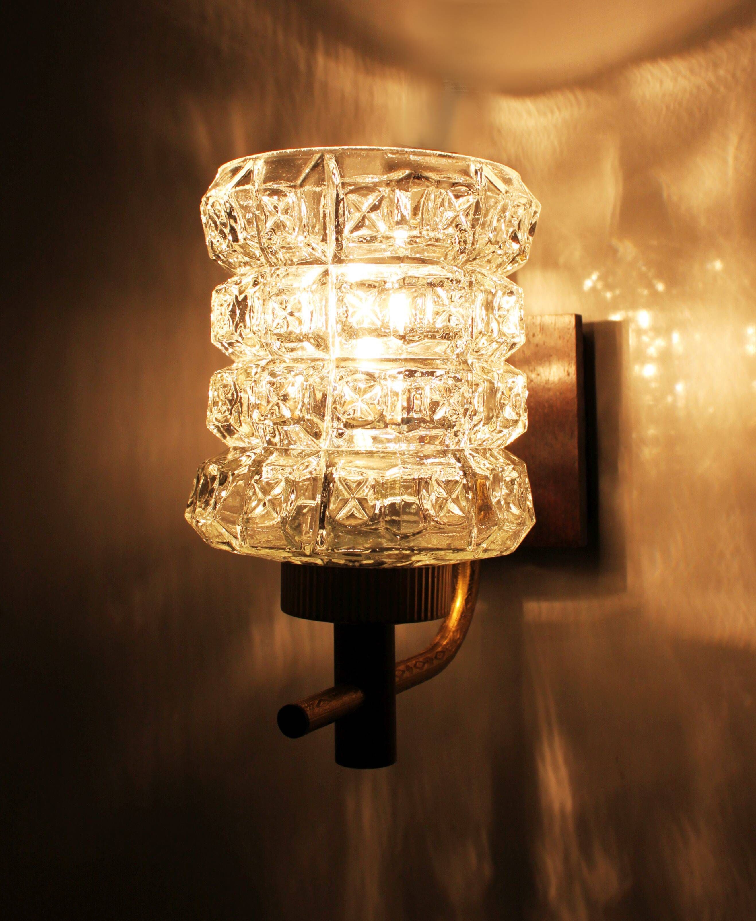 Pair of wall sconces in textured glass, wood, and gold metal, 1970.